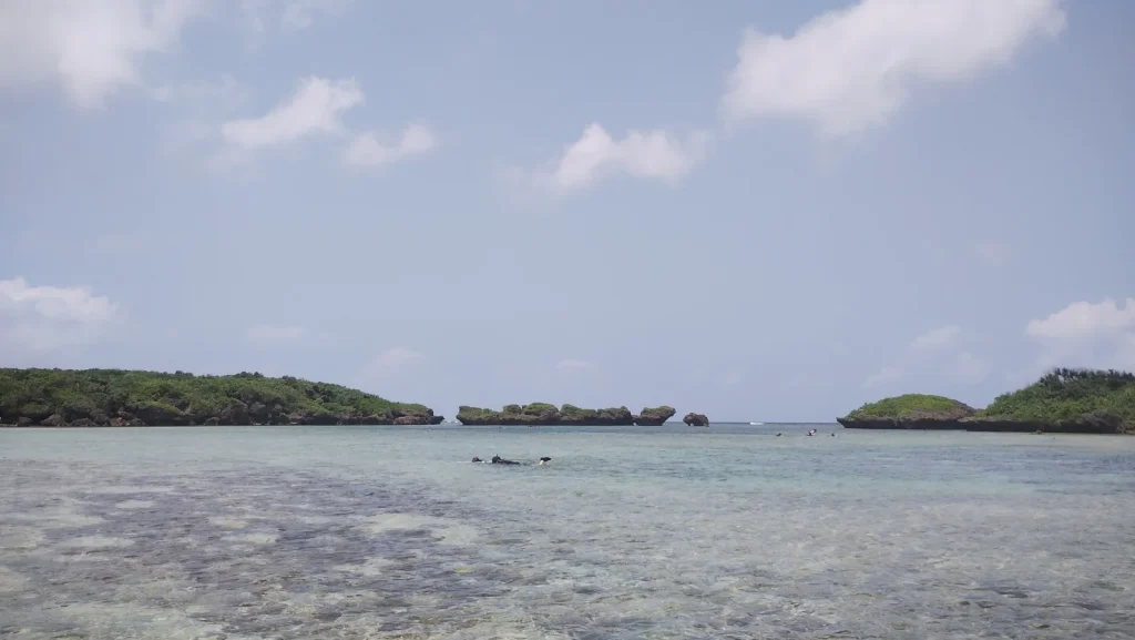 浅く透明な海と沖に岩礁が見える西表島のビーチ