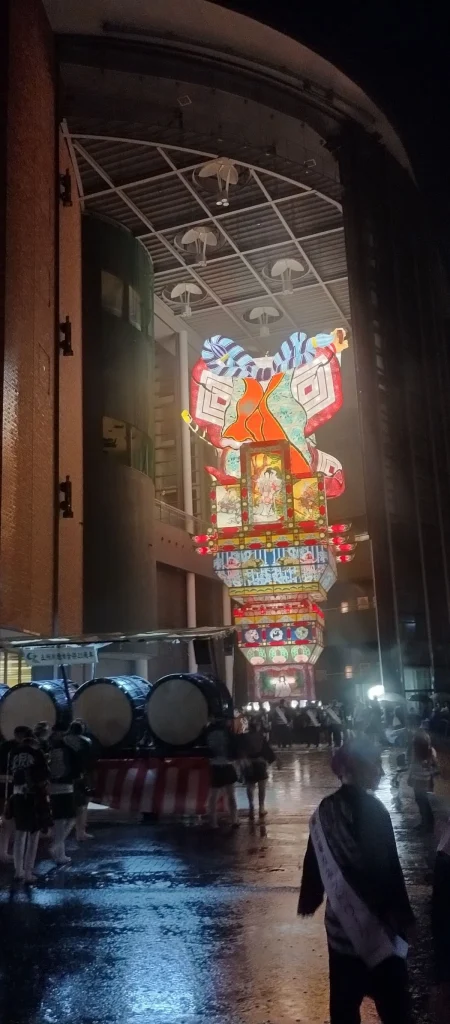 雨で濡れた五所川原の夜を進む立佞武多と太鼓
